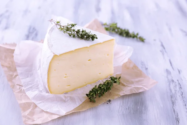 Tasty Camembert cheese with thyme, on wooden table — Stock Photo, Image