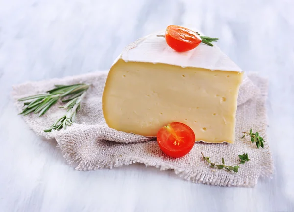 Sabroso queso Camembert con romero y tomate, sobre mesa de madera —  Fotos de Stock