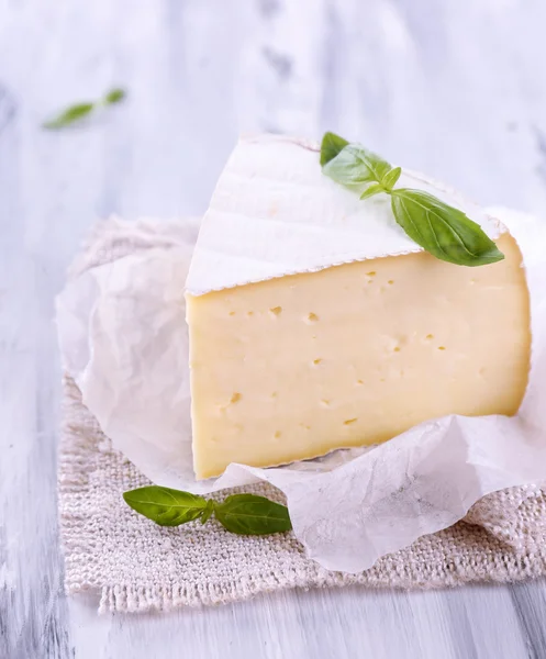Tasty Camembert cheese with basil, on wooden table — Stock Photo, Image