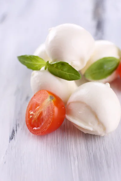 Tasty mozzarella cheese with basil and tomatoes, on wooden table — Stock Photo, Image