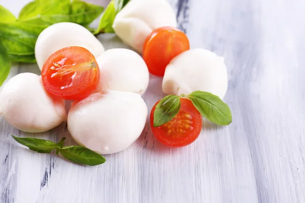 Tasty mozzarella cheese with basil and tomatoes, on wooden table — Stock Photo, Image