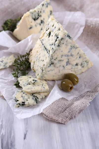 Queijo azul saboroso com tomilho e azeitonas em papel — Fotografia de Stock