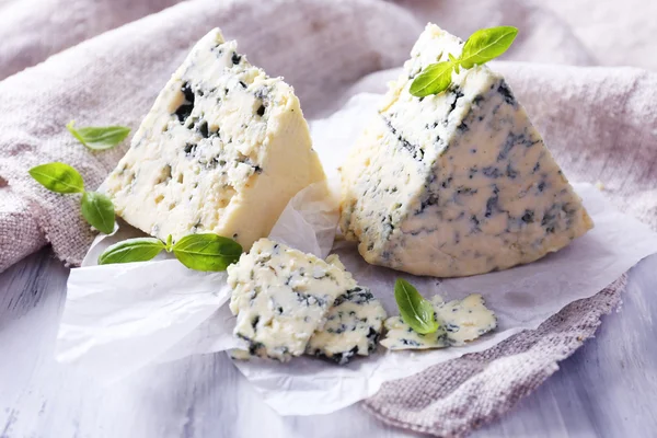 Queijo azul saboroso com manjericão sobre papel — Fotografia de Stock