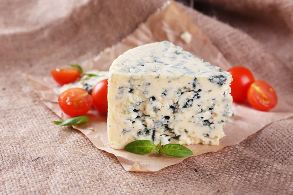 Chutné modrý sýr s rajčaty a bazalkou, na pozadí pytlovina — Stock fotografie