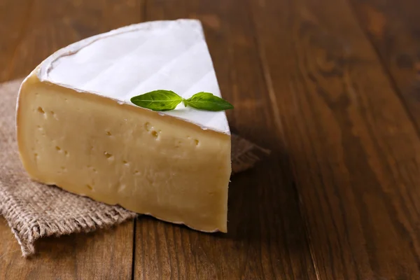 Sabroso queso Camembert con albahaca, sobre mesa de madera —  Fotos de Stock