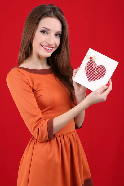 Mulher atraente com cartão postal, no fundo vermelho — Fotografia de Stock