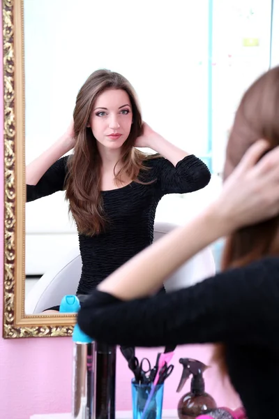 Joven hermosa mujer sentada frente al espejo en la habitación —  Fotos de Stock