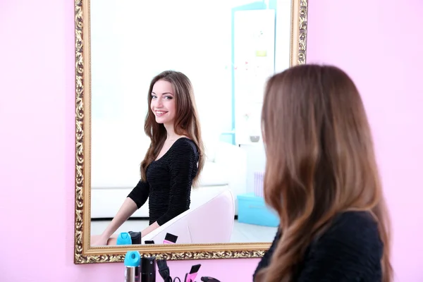 Young beautiful woman sitting front of mirror in room — Stock Photo, Image