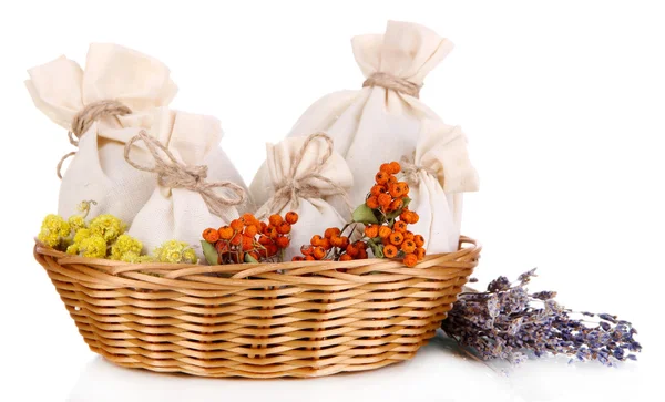 Textile sachet pouches with dried flowers, herbs  and berries  in wicker basket, isolated on white — Stock Photo, Image