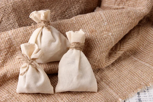 Jute bags on sackcloth, on wooden background — Stock Photo, Image