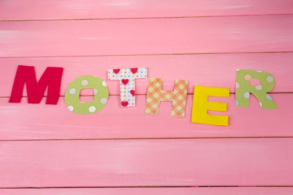 Mother- lettering of handmade paper letters on pink wooden background — Stock Photo, Image