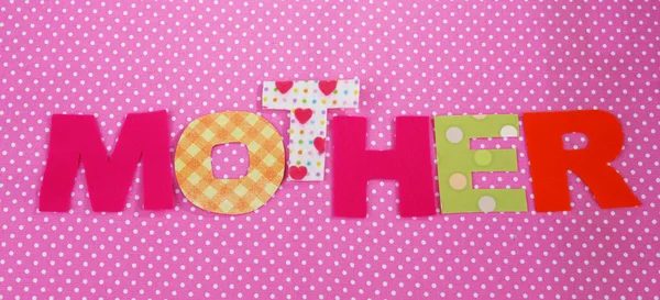 Mother- lettering of handmade paper letters on pink polka background — Stock Photo, Image