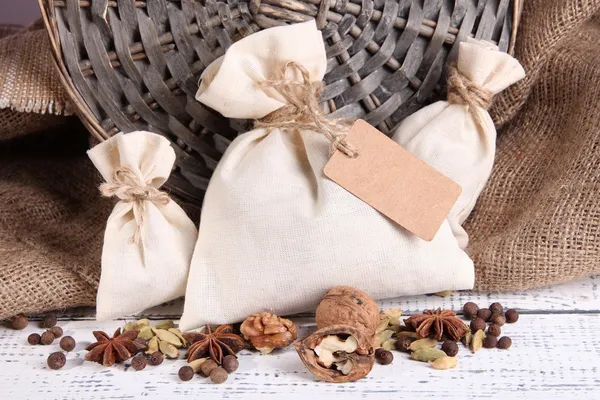 Sacks full with spices, on wooden table, on sackcloth background — Stock Photo, Image