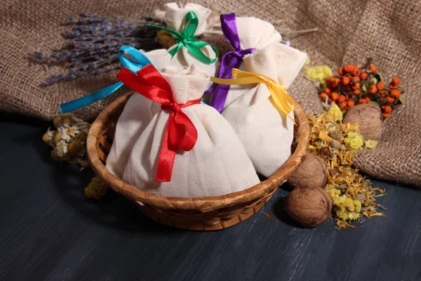 Bolsas de bolsitas textiles con flores secas, hierbas y bayas sobre mesa de madera, sobre fondo de saco —  Fotos de Stock