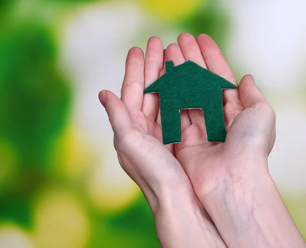 Piccola casa di carta in mano primo piano, su sfondo luminoso — Foto Stock