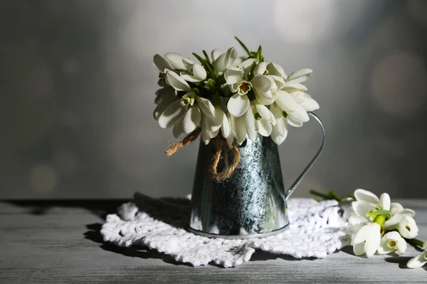 Bonitas gotas de neve em vaso de metal em fundo cinza — Fotografia de Stock