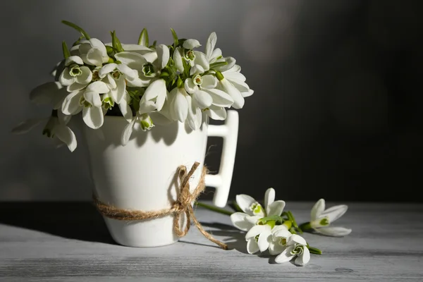 Beautiful snowdrops in cup on grey background — Stock Photo, Image