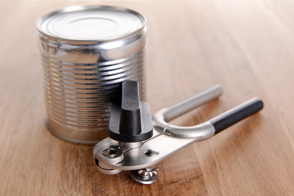 Can piercer with canned on wooden background — Stock Photo, Image