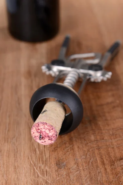 Corkscrew with bottle of wine on wooden background — Stock Photo, Image