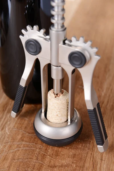 Corkscrew with bottle of wine on wooden background — Stock fotografie