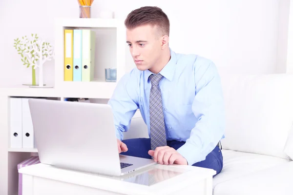 Snygg ung man som jobbar på laptop hemma — Stockfoto