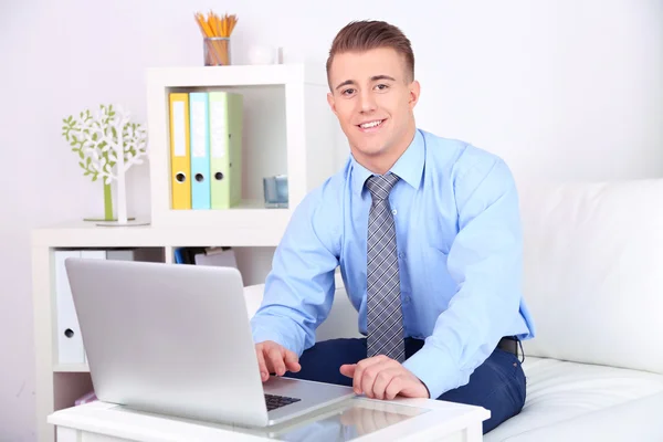 Jovem bonito trabalhando no laptop em casa — Fotografia de Stock