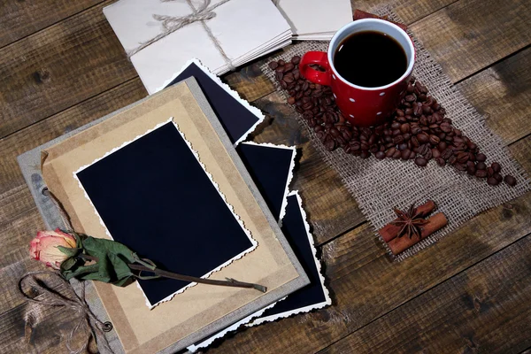 Samenstelling met koffie beker en fotoalbum, op houten achtergrond — Stockfoto