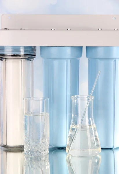 Filtersystem zur Wasseraufbereitung mit Glas und Glühbirne auf hellem Hintergrund — Stockfoto