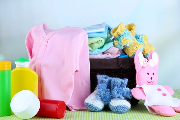 Hromadu dětské oblečení v koši, na stole na barvu pozadí — Stock fotografie
