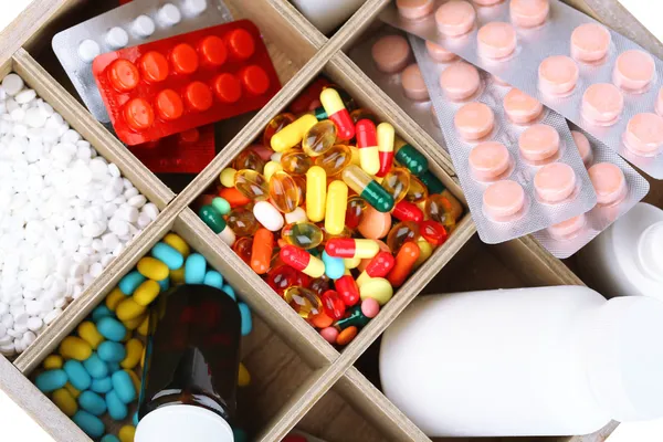Медицинские таблетки, ампулы в деревянной коробке, крупный план — стоковое фото
