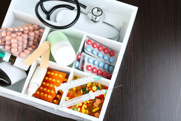 医疗丸、 听诊器、 安瓿在彩色背景上的木盒子里 — 图库照片