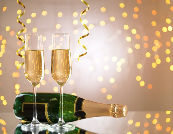 Copos e garrafa de champanhe sobre fundo brilhante — Fotografia de Stock