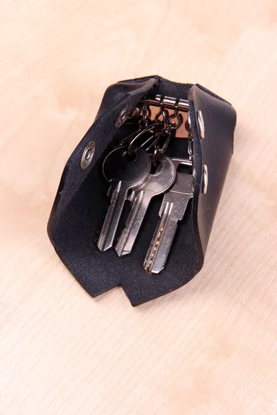 Black leather key case on wooden background — Stock Photo, Image