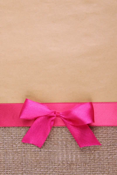 Saco con cinta de color y lazo sobre fondo de papel de color — Foto de Stock