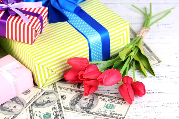 Geschenkdozen met geld en bloemen op een houten achtergrond kleur — Stockfoto