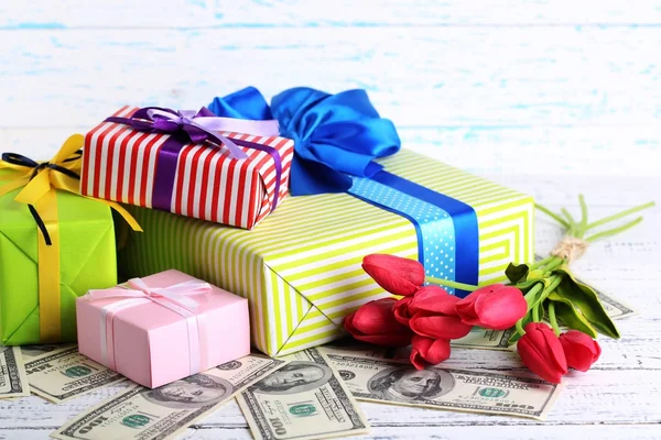 Presentförpackning med pengar och blommor på färg trä bakgrund — Stockfoto