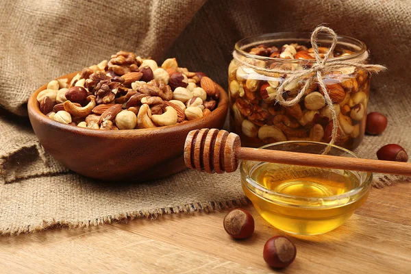 Miel dulce y diferentes frutos secos en mesa de madera — Foto de Stock