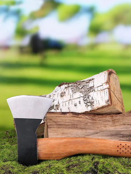 Ax y leña sobre hierba verde, sobre fondo natural — Foto de Stock