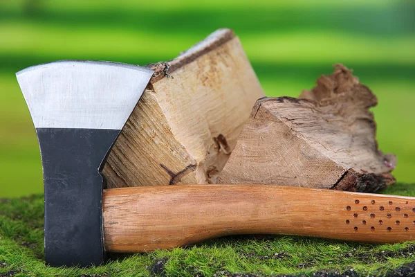 Ax e lenha na grama verde, no fundo da natureza — Fotografia de Stock