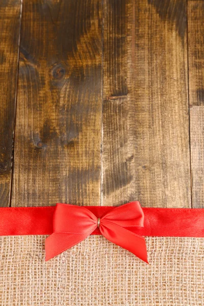 Sackcloth with color ribbon and bow on wooden background — Stock Photo, Image