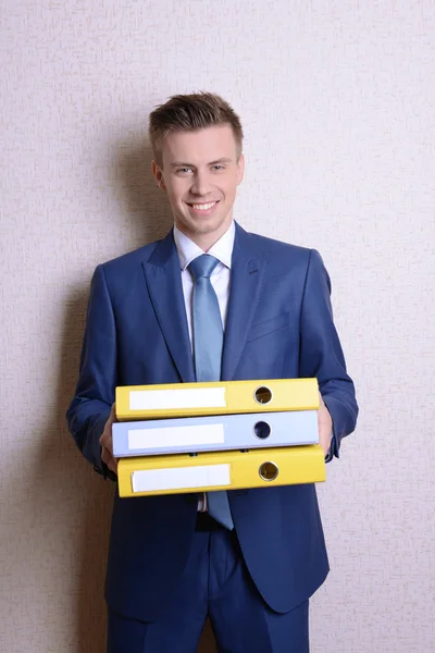 Portrait of businessman with folders near wall — Stock Photo, Image