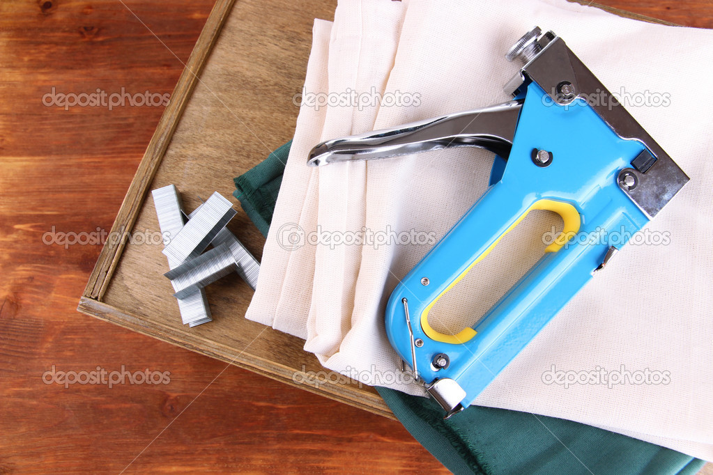 Construction stapler with fabrics and staples on wooden background