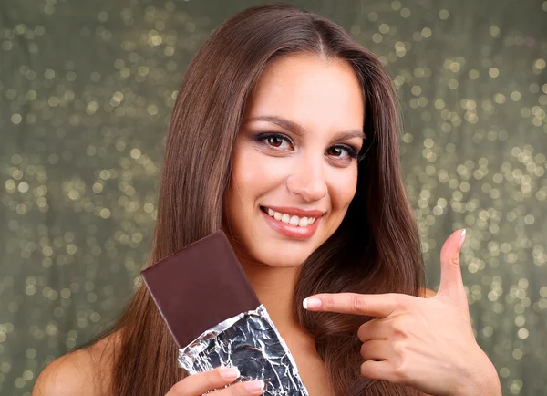 Portret van mooie jonge meisje met chocolade op glanzende achtergrond — Stockfoto