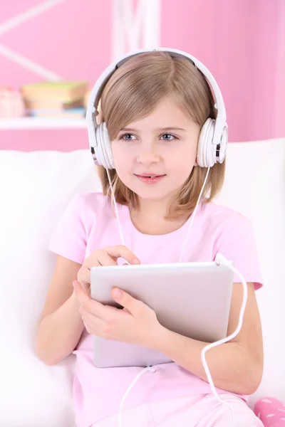 Niña sentada en el sofá y escuchando música en la habitación — Foto de Stock