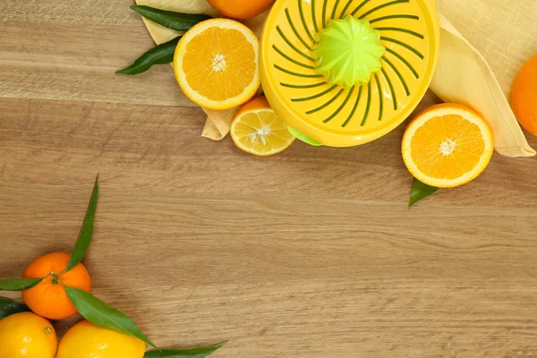 Citrus press and fruits on wooden background — Stock Photo, Image