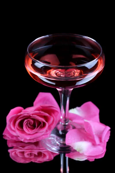 Σύνθεση με ροζ λάμψη κρασί σε ποτήρι και τριαντάφυλλο που απομονώνονται σε μαύρο — Φωτογραφία Αρχείου