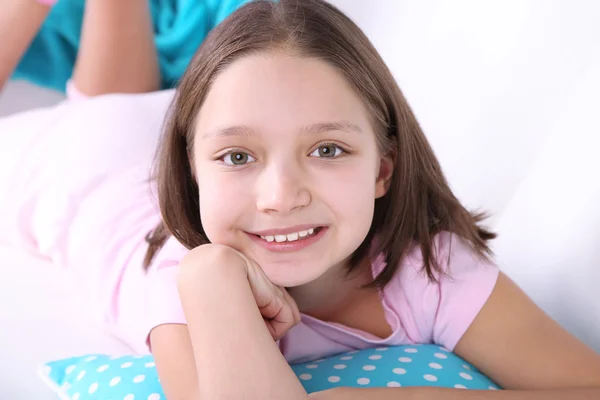 Hermosa niña sentada en el sofá con libro, en el fondo interior de casa —  Fotos de Stock