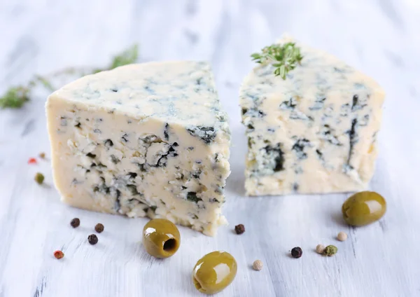 Вкусный синий сыр с тимьяном и оливками на деревянном столе — стоковое фото
