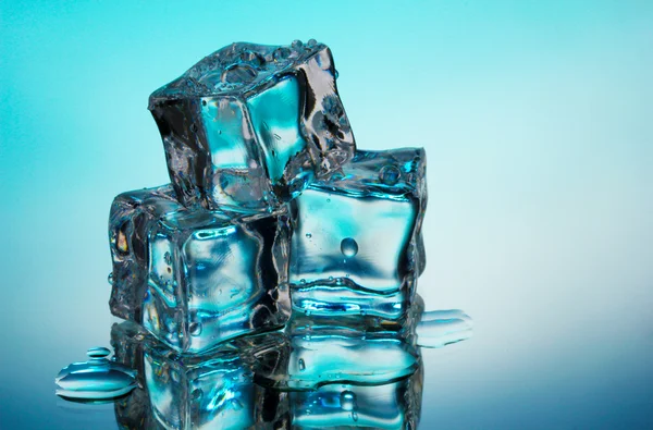 Cubes de glace fondus sur fond bleu — Photo