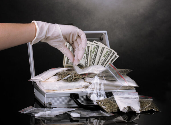 Cocaine and marijuana in a suitcase wiht hand holding a package of cocaine isolated on white